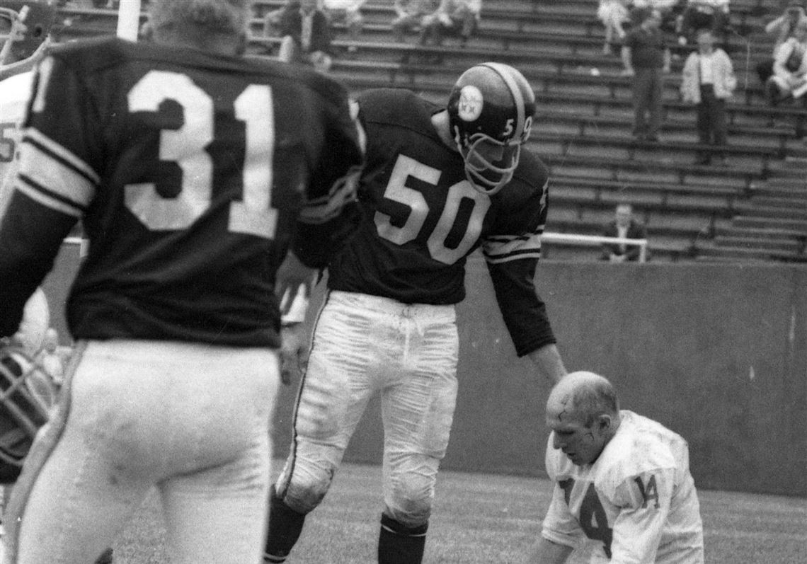 Steeler Bill Saul checks on New York Giants quarterback Y.A. Tittle, who kneels in the end zone at Pitt Stadium after a sack by Steeler defender John Baker on Sunday, Sept. 20, 1964.