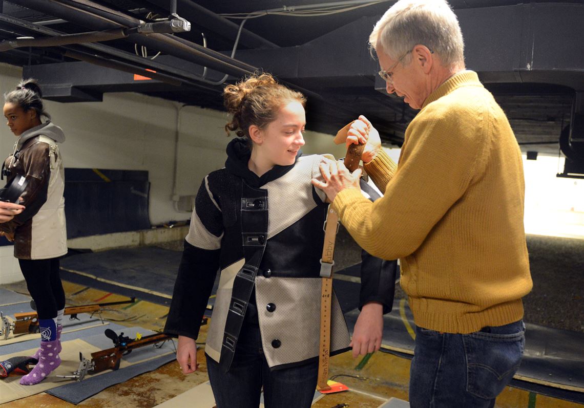 In this file photo from Dec. 17, 2013, Mt. Lebanon rifle team coach Dave Willard tightens a sling onto Emily Lackner, a junior, as they prepare for a match against Woodland Hills at the Mt. Lebanon rifle range.  