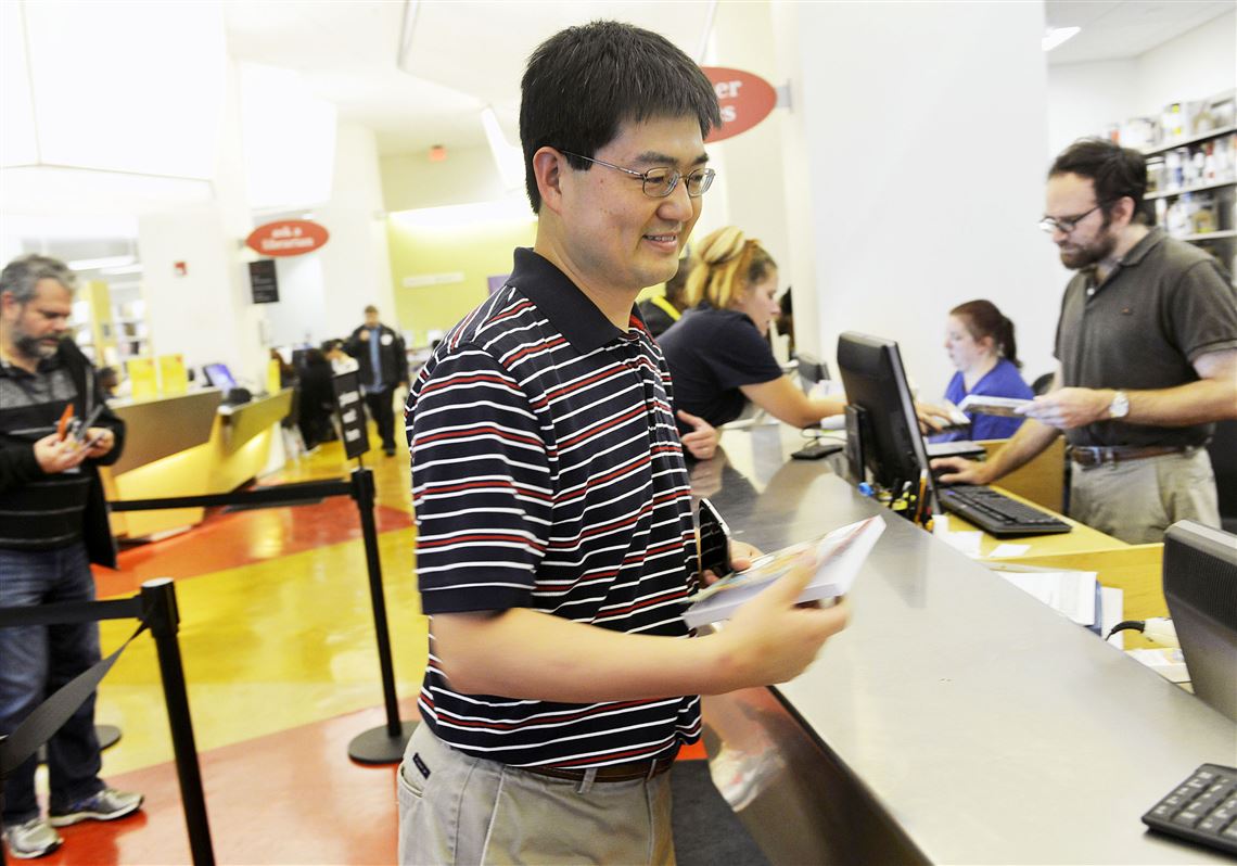 In this 2014 photo, Wu Lu, from Franklin Park, picks up a copy of a book requested online by his daughter at the Downtown branch of the Carnegie Library.