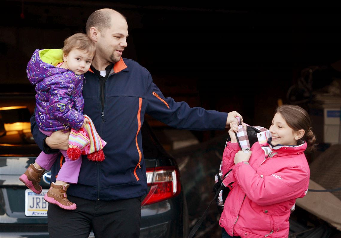 Rev. Jason Charron, a priest at Holy Trinity Ukrainian Catholic Church in Carnegie, carries his youngest daughter Natalia, 1, while helping another of his daughters Katya, 10, with her backpack after driving them home in January. Charron is married and has six daughters.  