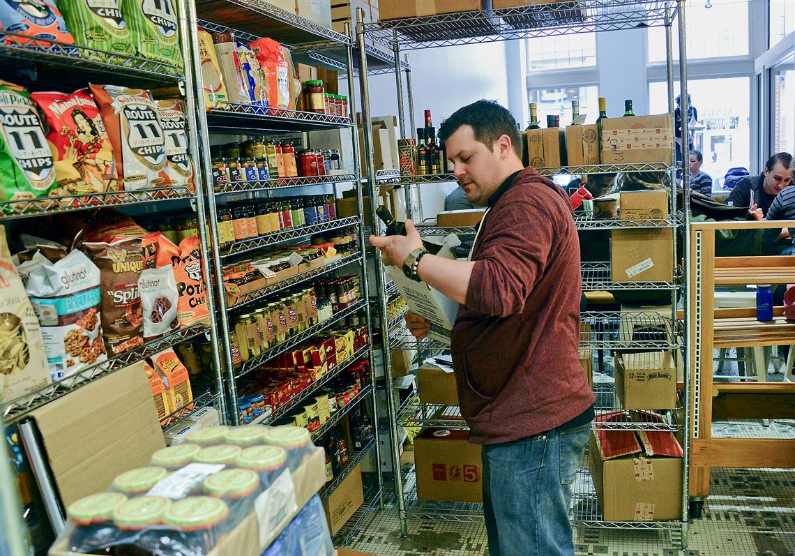 Dan Rencewicz, general manager of Market Street Grocery, stacks products Tuesday at the new store in Market Square, Downtown.