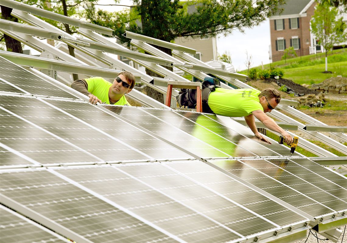 In this May 21, 2015, file photo, Brian Krenzelak, left, and Scott Rhodehamel of Energy Independent Solutions install solar panels in Moon.