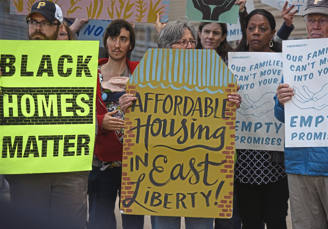 About 35 people gathered on Thursday, April 26, 2018, in the shadow of the David L. Lawrence Convention Center, Downtown, to discuss the impact Amazon's HQ2 would having on housing in Pittsburgh. Holding signs are, from left, Patrick Young of Fineview, Emily DeFerrari of Point Breeze, Carol Hardeman of the Hill District and John Haer of Park Place. (Steve Mellon/Post-Gazette)
