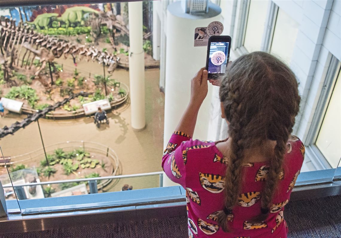 Juliette Heiby, 9, of Venetia, scans the Andy CarnegieBot barcode on her cell phone at Carnegie Museum of Natural History in Oakland. She and her mom, Julianna, helped develop the scavenger hunt for the Facebook Messenger guide to the museums.