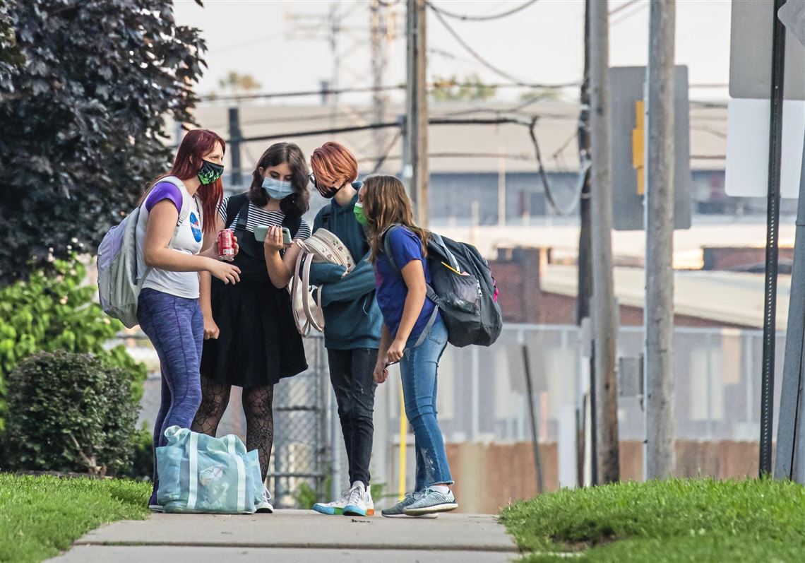 Students wait at a bus stop near Ambridge Area Senior High School on the first day of Pennsylvania's mask mandate for K-12 schools and day care centers on Tuesday, Sept. 7, 2021, in Ambridge.   