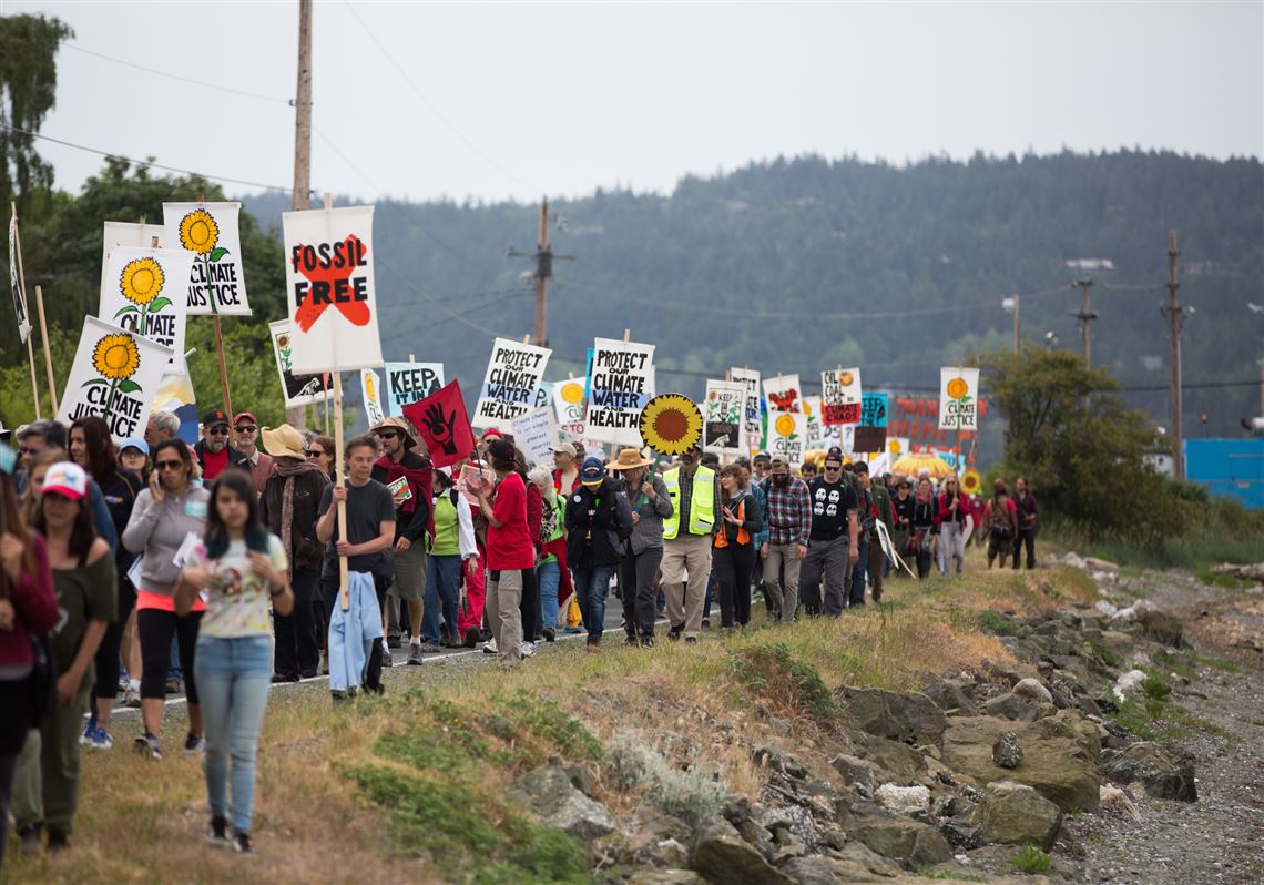 Break Free PNW kayaktivists unfurl their banner while out on the water in Fidalgo Bay east of Seafarer's Memorial Park in Anacortes, Wash., Friday, May 13, 2016. Hundreds of people in kayaks and on foot are gathering at the site of two oil refineries in Washington state to call for action on climate change and a fair transition away from fossil fuels. Behind is a U.S. Coast Guard vessel near the March Point refineries loading dock. (Scott Terrell/Skagit Valley Herald via AP) MANDATORY CREDIT
