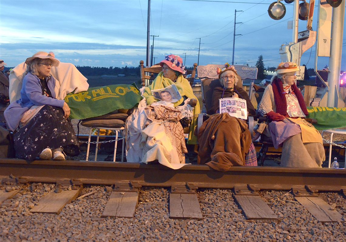 Members of the Seattle Raging Grannies sit in their rocking chairs chained together on the Burlington-Northern Railroad tracks at Farm to Market Road in Skagit County on Friday evening, May 13, 2016, in Burlington, Wash.  From left are Deejay Sherman Peterson, Anne Thureson, Shirley Morrison and Rosy Betz-Zall. Hundreds of people in kayaks and on foot are gathering at the site of two oil refineries in Washington state to call for action on climate change and a fair transition away from fossil fuels. (Scott Terrell/Skagit Valley Herald via AP) MANDATORY CREDIT 