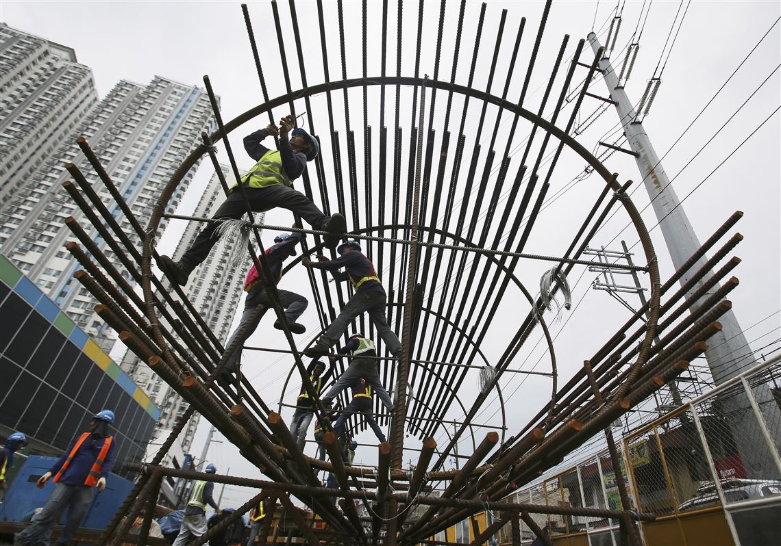 In this Aug. 12, 2015, file photo, workers arrange metal rods at a government road project in suburban Quezon City.