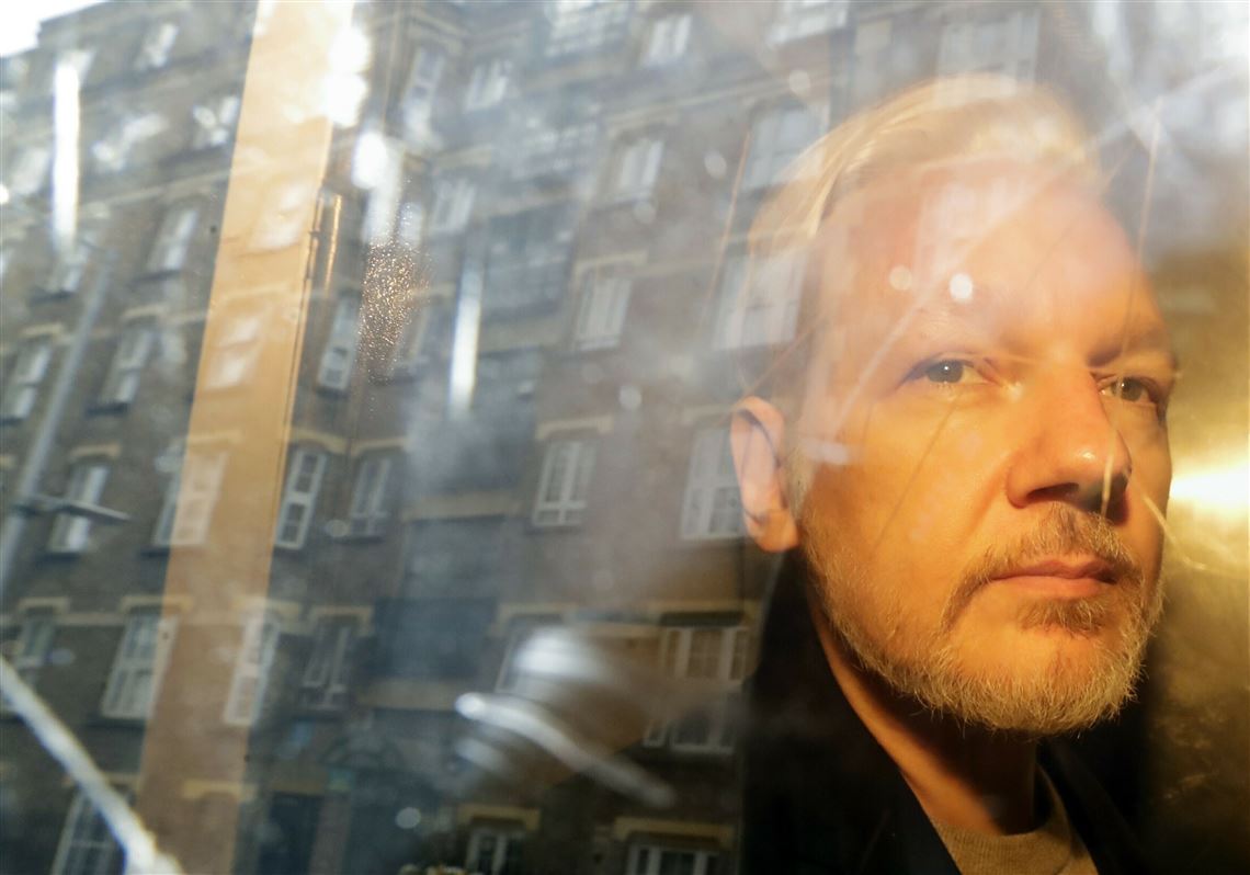 In this Wednesday May 1, 2019 file photo, buildings are reflected in the window as WikiLeaks founder Julian Assange is taken from court, where he appeared on charges of jumping British bail seven years ago, in London. 