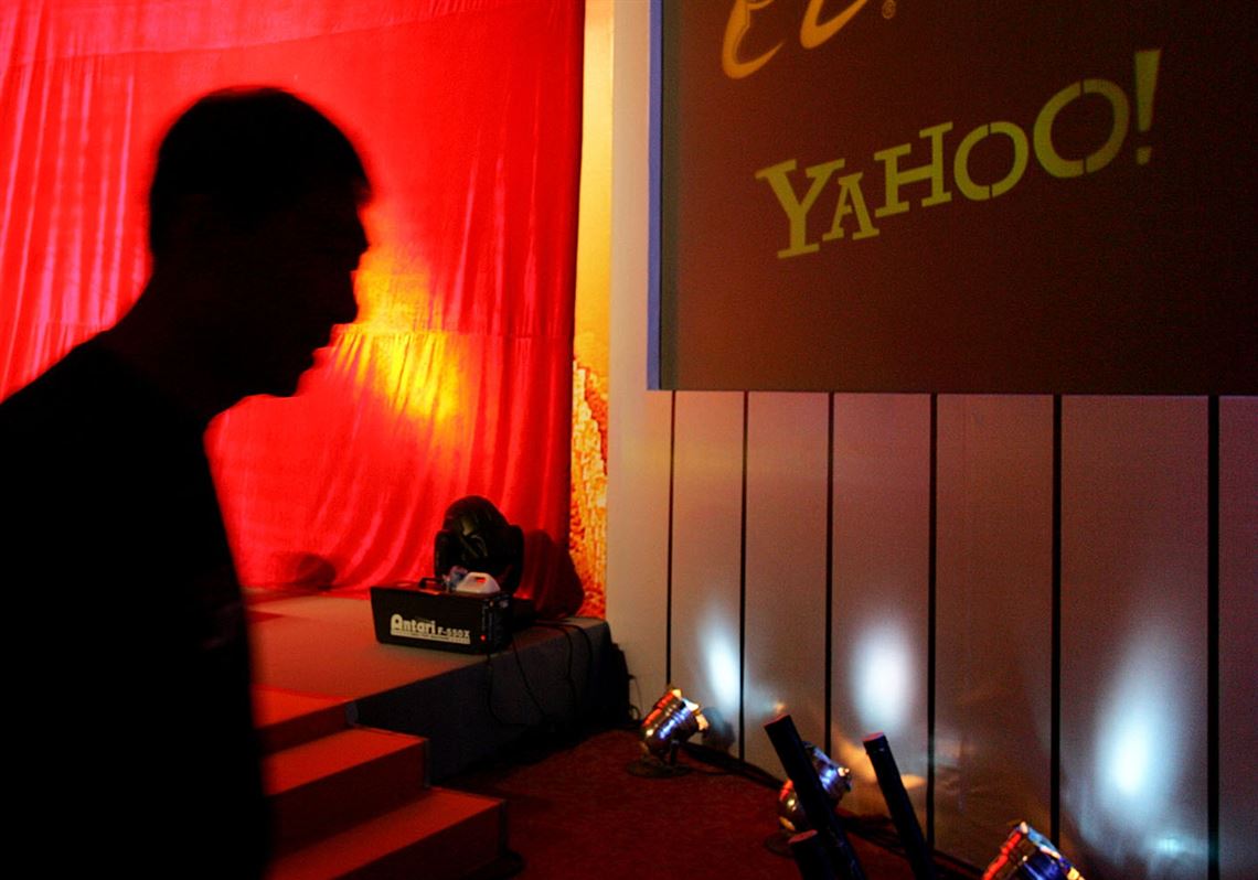 A man walks past a screen displaying the Yahoo logo before a joint news conference by the companies at the China World Hotel in Beijing on Aug. 11, 2005. Yahoo Inc. said on Tuesday that it is pulling out of China, citing an "increasingly challenging business and legal environment."