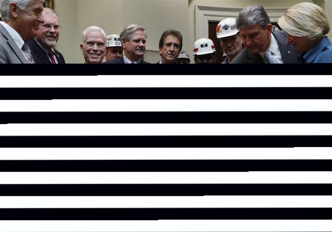 FILE - In this Feb. 16, 2017 file photo, Sen. Shelley Moore Capito, R-W. Va., right, Sen. Joe Manchin, D-W. Va., second from right, and coal miners, watch as President Donald Trump holds up H.J. Res. 38 after signing it in the Roosevelt Room of the White House in Washington. Lawmakers from coal-mining states are pushing to extend health benefits for more than 22,000 retired miners and widows whose live-saving medical coverage is set to expire at the end of April.  (AP Photo/Carolyn Kaster, File)