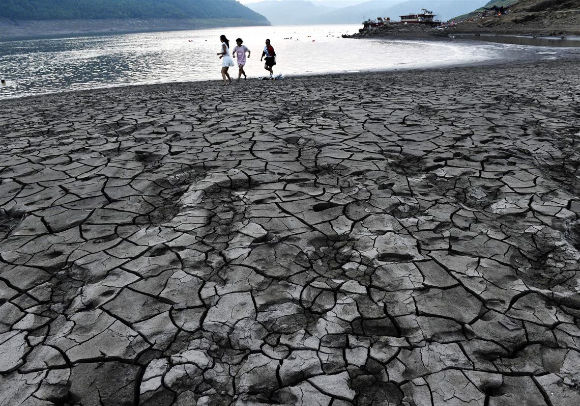 This file photo taken Aug. 24 shows people walking along the dried and cracked river beach of the Yangtze River in Yunyang county in Chongqing.