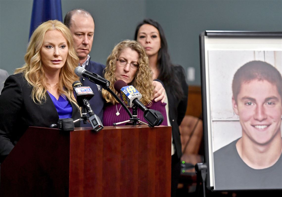 In this May 5, 2017, file photo, Centre County, Pa., District Attorney Stacy Parks Miller, left, announces findings in an investigation into the death of Penn State University fraternity pledge Tim Piazza, seen in photo at right, as his parents, Jim and Evelyn Piazza, second and third from left, stand nearby during a news conference in Bellefonte, Pa.   