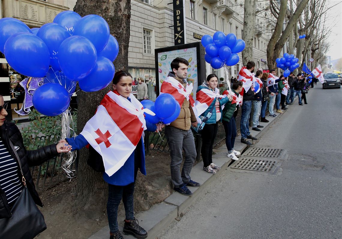 Supporters of the main opposition party wear Georgian national flags during a protest against buying gas from state-controlled Gazprom, in Tbilisi, Georgia, Sunday, March 6, 2016. Thousands of Georgians formed a human chain stretching for about 7 kilometers (4 miles) through the capital on Sunday to protest negotiations between their government and the Russian natural gas monopoly, Gazprom. (AP Photo/Shakh Aivazov)