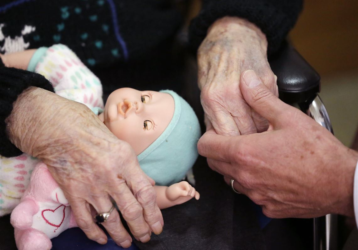 A son holds his mother's hand at her nursing home in Adrian, Mich.