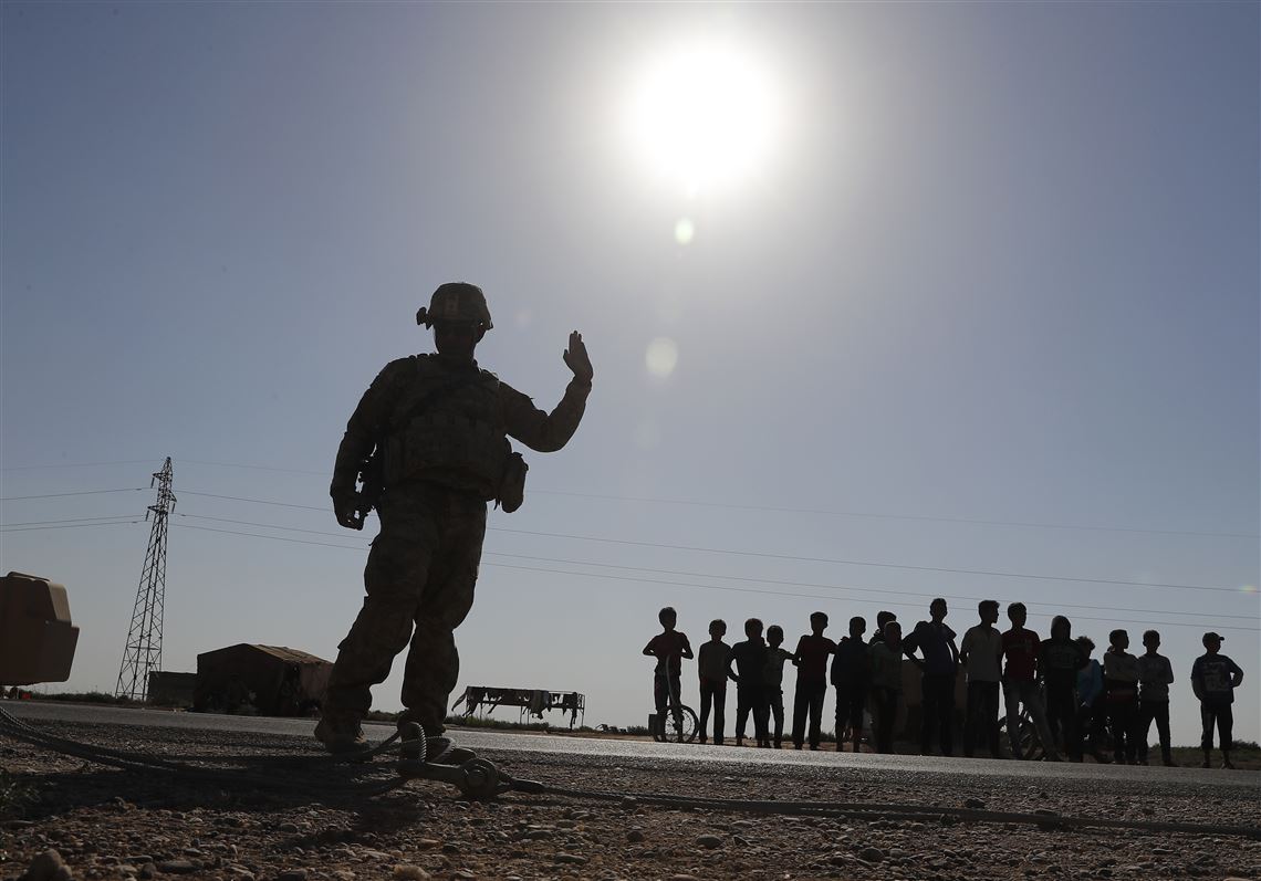 In this July 26, 2017, file photo, a U.S. soldier directs his armored convoy as Syrian children watch, on a road that leads to Raqqa, northeast Syria.
