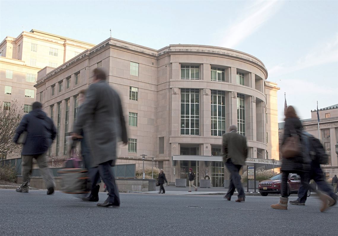 People walk by the Pennsylvania Judicial Center at the state Capitol in Harrisburg, Pa.