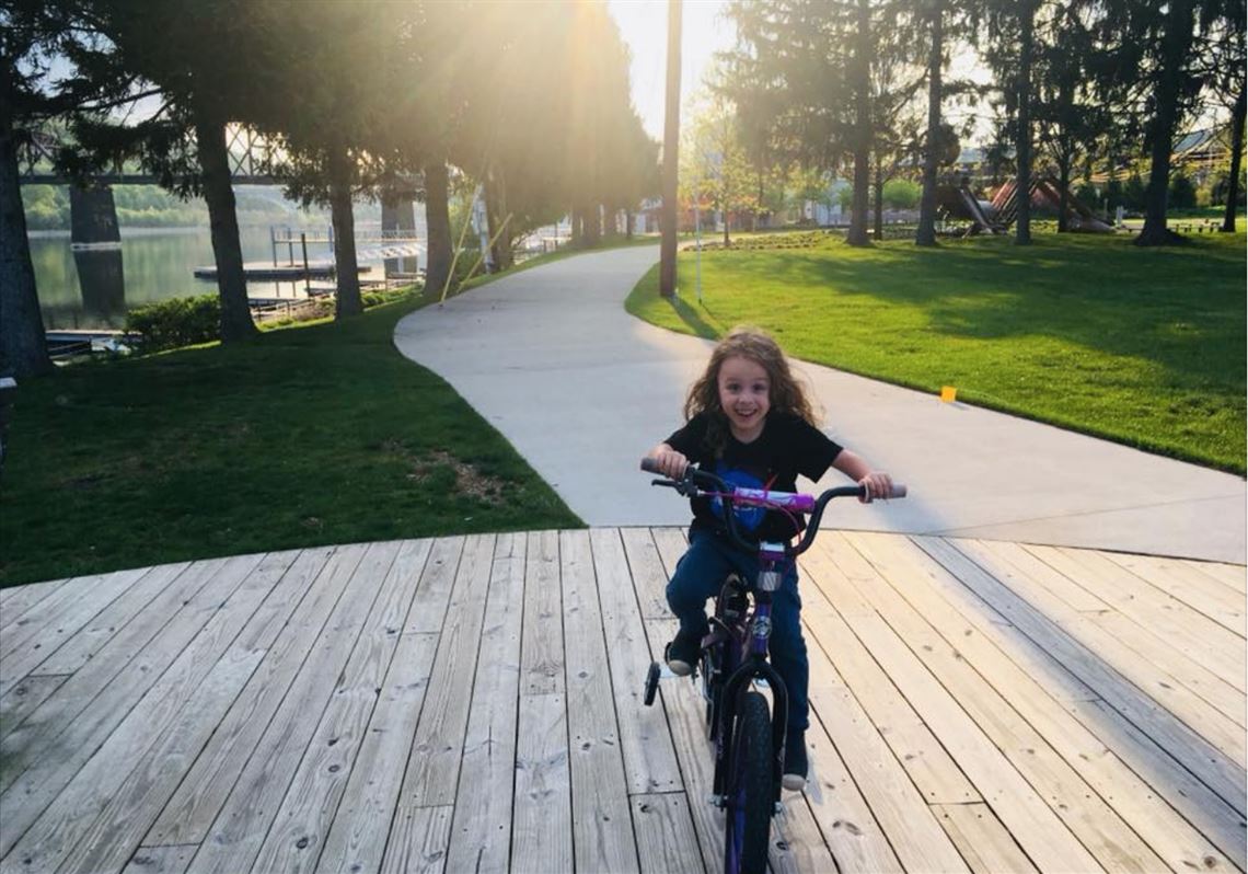 A young girl tries out her bike on the path at Aspinwall Riverfront Park.