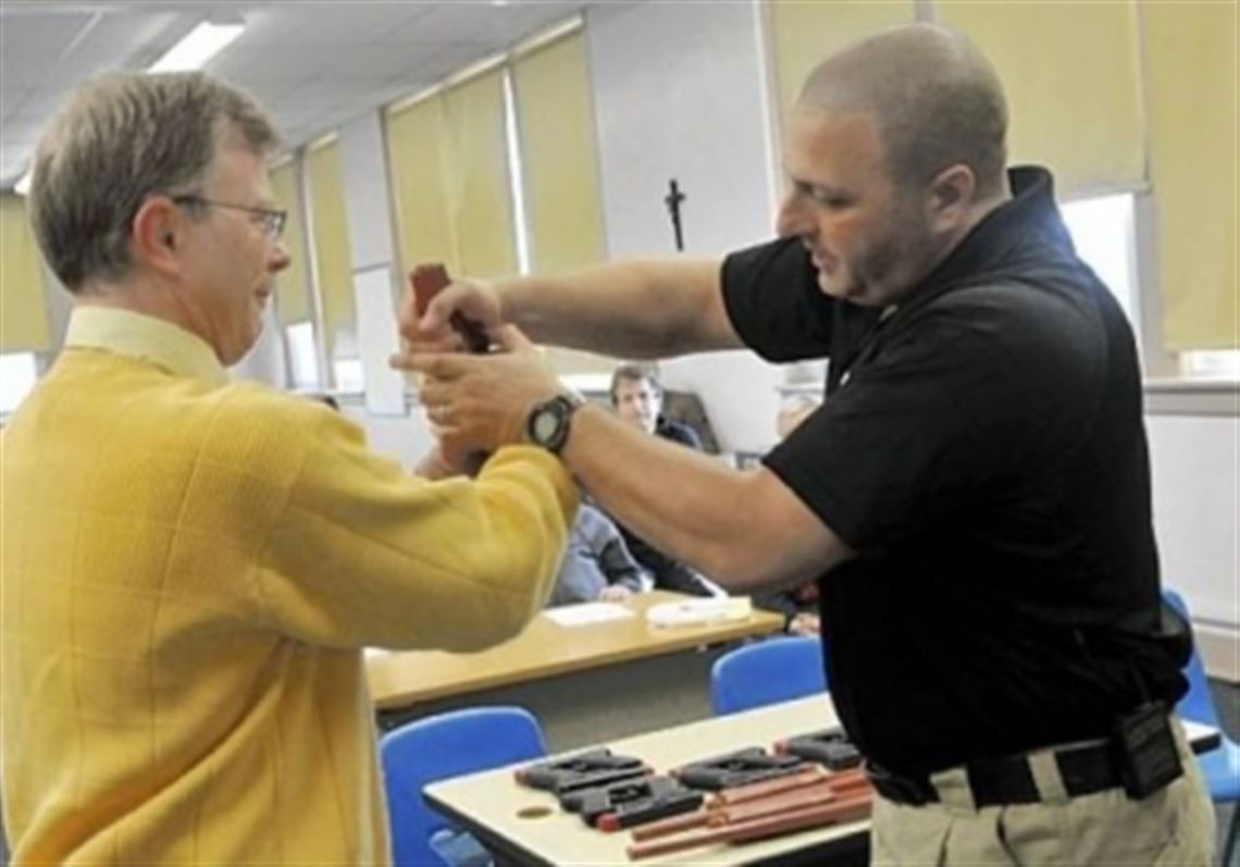 In this March 2013 file photo Sam Rosenberg, black shirt, shows North Catholic High School religion teacher Greg Evans, left, how to disarm a gun-wielding intruder at close range during a training session.