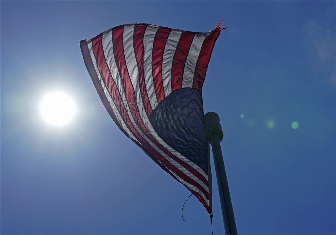 In this 2021 file photo, a U.S. flag flies with the sun in the background in downtown Seattle.