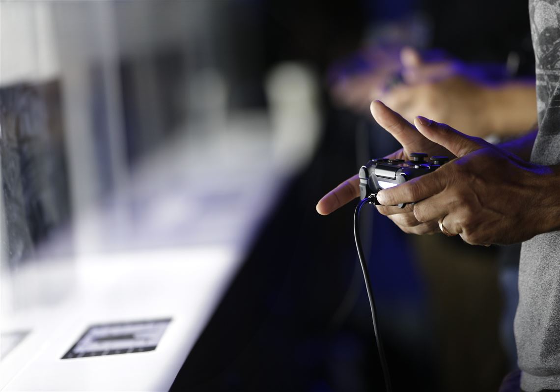 Attendees play video games on the PlayStation 4 at the Sony booth during the Electronic Entertainment Expo in Los Angeles in June 2013.