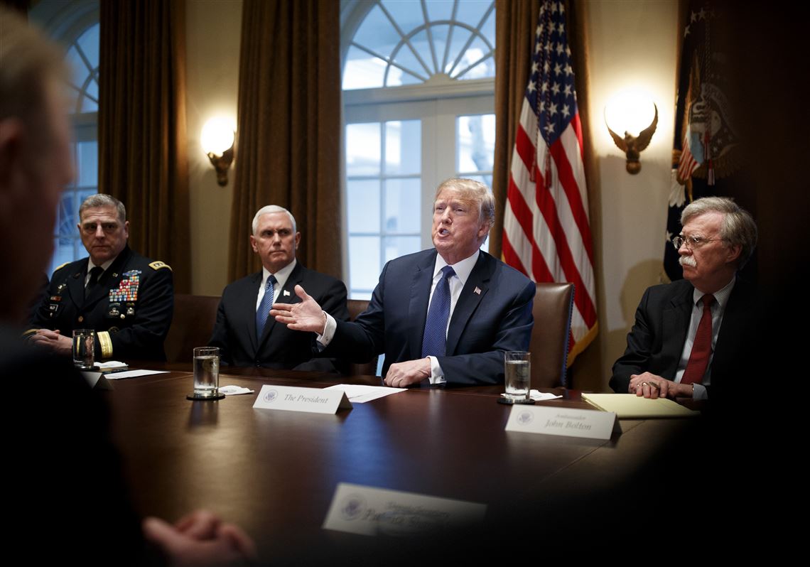 President Donald Trump is flanked by Vice President Mike Pence, left, and National Security Adviser John Bolton as he meets with senior military leaders at the White House in Washington on April 9, 2018.