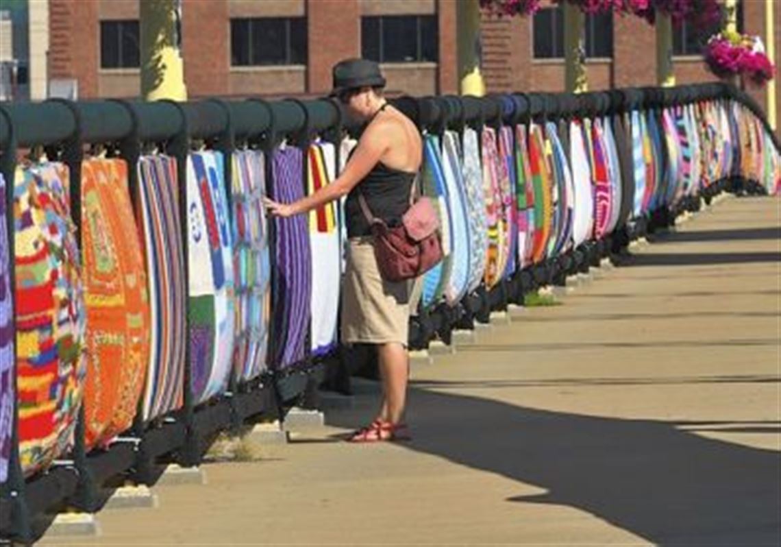 Kara Bender of Chicago on Wednesday feels the texture of one of the panels from the Knit the Bridge art installation on the Andy Warhol Bridge.
