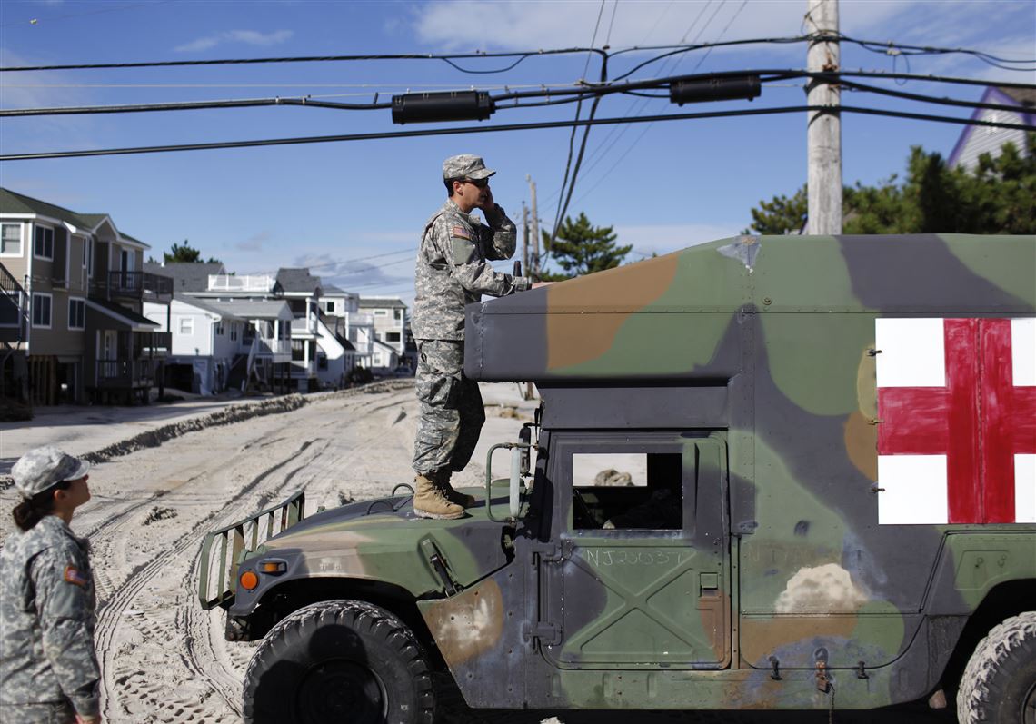 Kevin Cassano of the New Jersey National Guard stands atop a Humvee to gain better cellphone reception during the guard's patrol of Long Beach Island, N.J., in the aftermath of Superstorm Sandy Oct. 31, 2012. 