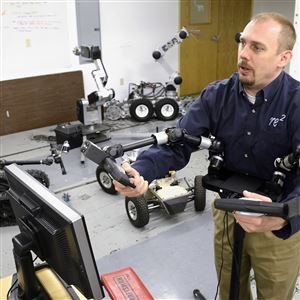 Jorgen Pedersen, president and CEO of RE2 in Lawrenceville, uses a mobile modular manipulation in the RE2 lab. The company also is developing a Patient Assist Robotic Arm, a robot that will help those with disabilities move to and from a wheelchair at home or in restaurants.