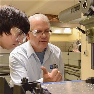 Western Pennsylvania School for the Deaf student Jonathan Border leans in to control a milling machine with the help of Tim Brandis of New Century Careers at the South Side training school.