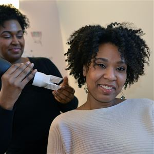 Tamiah Bridgett, founder of Diversame,  demonstrates a newly designed hair dryer on her sister, Grace Higginbotham. 