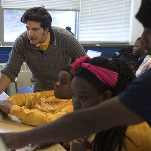 Alex Spergel, far left, and Haji Muya, far right, help students with Adobe Premiere at Propel's Andrew Street High School in Munhall.