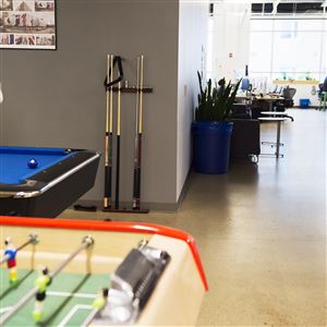 Duolingo employee Amanda Strader plays pool as Bunny, a 15-year-old West Highland White Terrier owned by CEO Luis von Ahn, looks on in March at the company's East Liberty headquarters.