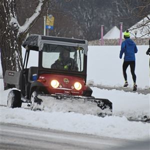 Snow is cleared from the bike lane in front of Phipps Conservancy and Botanical Gardens as runners go by February 12, 2018 in the Oakland section of Pittsburgh.