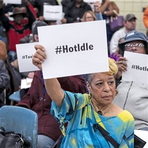Attendees including Cheryl Hurt, center, of Clairton hold up signs referring to community members' desire to temporarily halt production at Clairton Coke Works during a community meeting to discuss air quality problems caused by a December 24 fire, at Clairton City Hall, Tuesday, Jan. 22, 2019, in Clairton. 