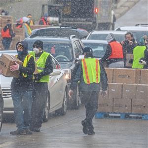 Volunteers load cars in line for an emergency drive-up food distribution from the Greater Pittsburgh Community Food Bank in a parking lot outside PPG Paints Arena on April 10 in Uptown.  The bank planned to serve 1,300 vehicles. 