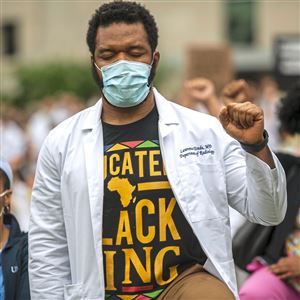 Dr. Lawrence Urado kneels and raises his fist during a tribute to George Floyd on June 5, 2020, on the lawn of UPMC Presbyterian Hospital in Oakland.