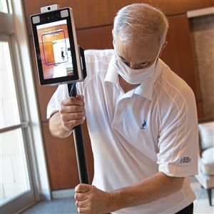 Peoples Natural Gas spokesman Barry Kukovich adjusts the thermal scanner that checks employees' temperatures as they enter the company's headquarters building on the North Shore. The scanner also checks for face masks. 