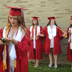 McKeesport Area High School graduate Madison Kwiecinski, front, checks her cellphone before taking photos with her friends Carlie Humanic, Keira Shields and Cassidy Newmyer after their graduation ceremony on Tuesday, June 30, 2020.