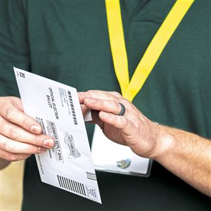 Tom Lyon, of Kennedy, a poll worker with the Allegheny County Elections Division, confirms the information on the outer envelope of a voter's mail-in ballot at the satellite election office and mail-in ballot drop-off location at the North Park Ice Rink in McCandless on Saturday, Oct. 10, 2020.