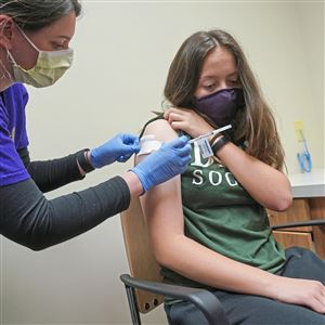 Pharmacist Stephanie Mavrodin, left, applies a bandage to the arm of Maria Lamberty, 14, of Squirrel Hill after Lamberty received a dose of the Pfizer COVID vaccine at UPMC’s South Side facility on Wednesday, May 12, 2021. 