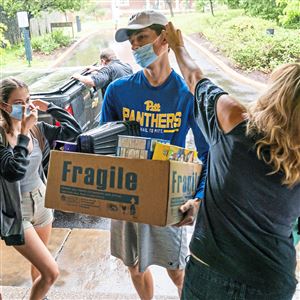 Nicole Wertz, right, helps her son Brendan adjust his mask as he helps his sister, Bailey, left, move into her dorm room at Chatham University on move-in day on Wednesday, Aug. 18, 2021. 