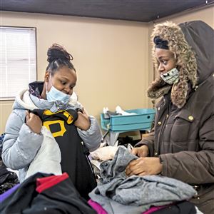 Coryonna Bertram shows a Pirates jersey to her mother Monique Demery, former residents of the Rodi Arms Apartments which was destroyed in a fire early Saturday morning, as they look through clothing at the Western Pennsylvania Search and Rescue Development Center, Monday, Jan. 24, 2022, in Penn Hills. Coryonna said she was sad that several of her Pittsburgh sports jerseys were destroyed in the fire. The organization received hundreds of donations including bags of clothing, food, and other necessities, and monetary donations after putting out a call for donations to help the more than 60 people displaced by the fire. (Alexandra Wimley/Post-Gazette)