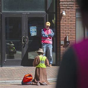 An unidentified person prays outside the Von Maur department store