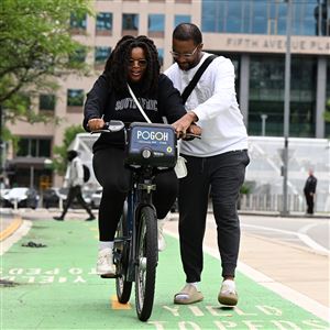 Will Tate, 33, of Green Tree, teaches his wife Mulalo Tate, 32, to ride a bicycle on a POGOH ride share bike on Penn Ave. near Point State Park Downtown on Saturday, May 31, 2025. Will said the couple was trying to add another way to exercise together and decided to come downtown to give it a try. The POGOH ride share program celebrated its 10th year this weekend.