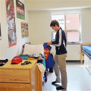 A student folds laundry in a bedroom in a three-bedroom-suite in Des Places Hall at Duquesne University.