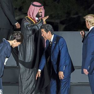 Japan’ Prime Minister Shinzo Abe checks his position with his wife, Akie Abe, as Saudi Arabia’s Crown Prince Mohammed bin Salman speaks to President Donald Trump on Friday during a photo session in front of Osaka Castle at the G-20 summit in Osaka, Japan.