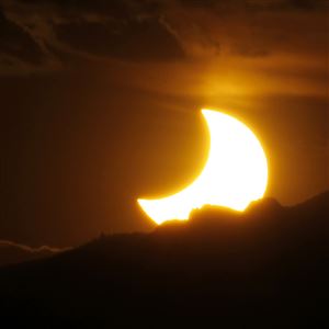 In this May 20, 2012, file photo, the annular solar eclipse is seen as the sun sets behind the Rocky Mountains from downtown Denver.