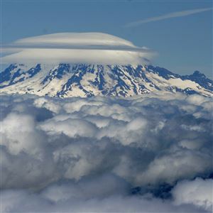 The summit of Mount Rainier, blanketed with cloud cover, as seen from the top of Mount St. Helens.
