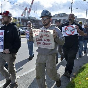 Justin Paetow, center, a tin shop worker at Bath Iron Works, takes part in a demonstration against a COVID-19 vaccine mandate outside the shipyard on Friday in Bath, Maine. Some American workers are making the painful decision to quit their jobs and abandon cherished careers in defiance of what they consider intrusive vaccine mandates requiring all businesses with 100 or more workers be fully vaccinated against COVID-19. 